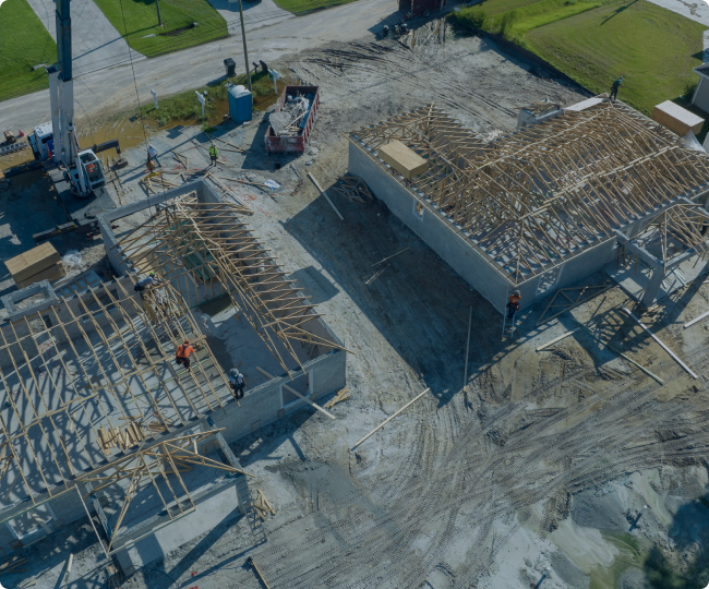 Aerial view of residential construction site with workers installing wooden roof framing on new houses