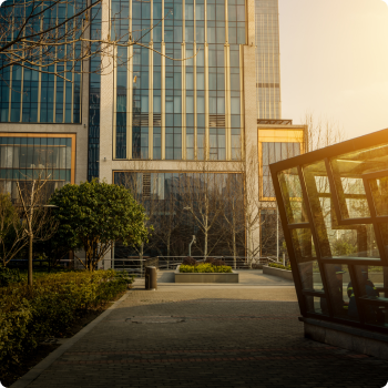 Modern glass office building with sunlight and green landscape